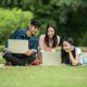 One man and two women having fun with their laptops in a park