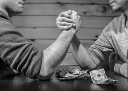 two men betting money on an arm-wrestle match