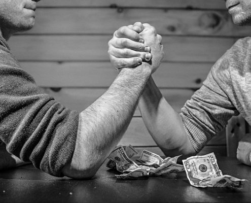 two men betting money on an arm-wrestle match