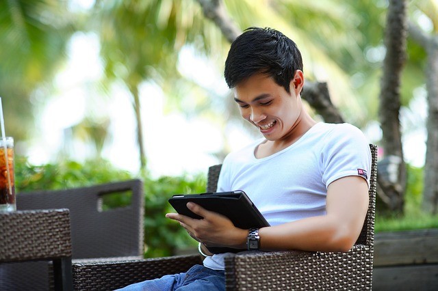 An asian man with his tablet device on a vacation