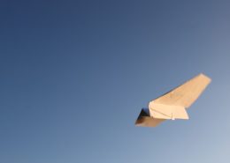 paper airplane flying in a clear blue sky