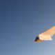 paper airplane flying in a clear blue sky